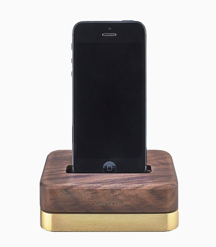 A wooden phone holder with an iphone on top of it.