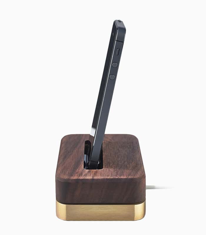A wooden and gold phone holder with a charging cable.