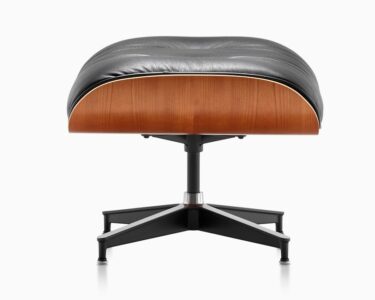 A black leather ottoman with wood and metal base.