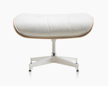 A white ottoman with a wooden frame and leather seat.
