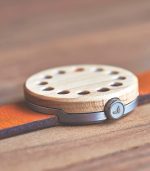 A wooden watch with a metal case on top of it.